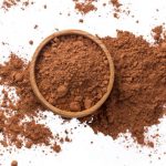 Cacao. Pile of cocoa powder in wooden bowl isolated on white background, top view